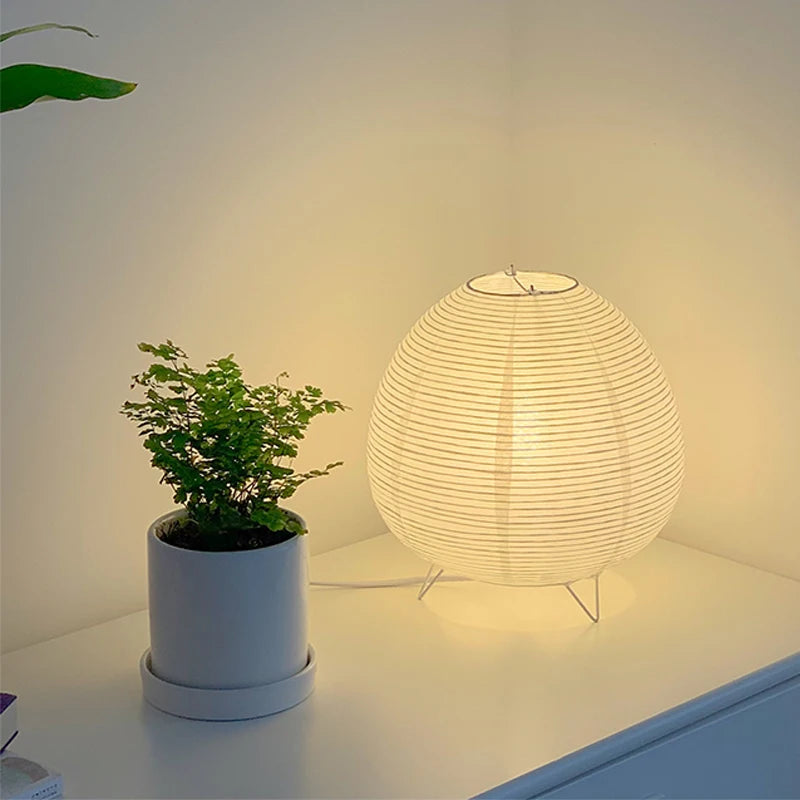 Paper globe lamp on a shelf beside a plant